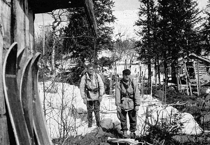 Her er Ola Holen (til venstre) og Kaare Bredesen tilbake i «Ambassaden», Grebegruppas hovedkvarter i Ruudshytta. De er utstyrt med tunge sekker, alltid rundt 40 kilo, våpen, og treski som ikke alltid gled like godt i djuprent og våt snø rundt påsketider i 1945.