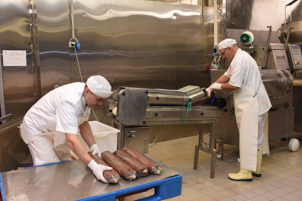 Toten Kjøtt produserer 1200 tonn i året. Halvparten av volumet er medisterfarse. Men bedriften lager en rekke produkter. Her er Slawomir Neuman (til venstre) og Besim Rushitic i ferd med å kjøre ut spekepølse.